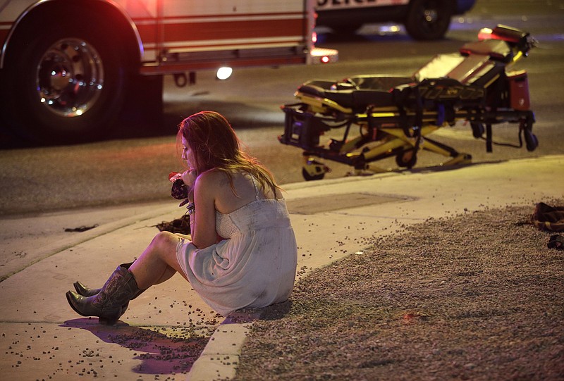 A woman sits on a curb at the scene of a mass shooting at a country music festival in Las Vegas on Sunday. At least 59 people were killed and more than 500 injured.