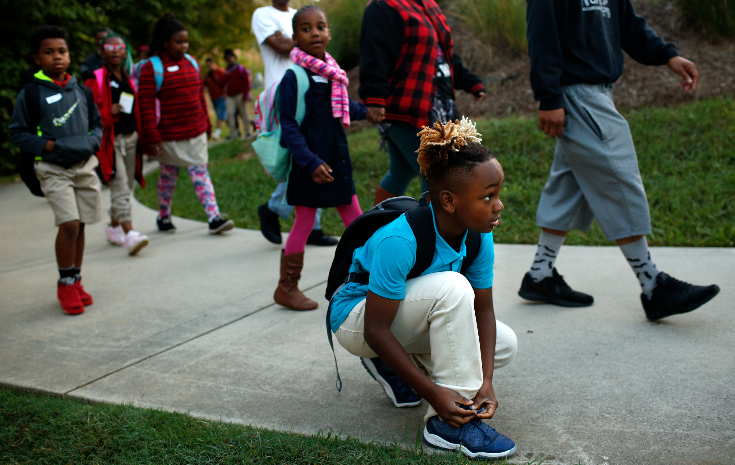 Brown Elementary student Chaise Tillman ties his shoe as he walks with other students from the University of Tennessee at Chattanooga's Challenger Center to school on East Eighth Street for International Walk to School Day on Tuesday, October 3, 2017, in Chattanooga, Tenn. Ten area schools have organized walk to school events this week in partnership with the Chattanooga-Hamilton County and North Georgia Transportation Planning Organizations.