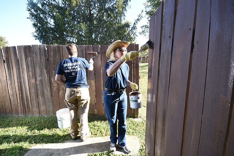 Lisa McKinney, right, and Dylan Brinn, employees at the Tennessee Valley Authority, volunteer and paint a wooden fence outside the administration building at the Chambliss Center for Children Thursday morning. The CFC Day of Serving saw about 300 federal employees volunteering at 22 local community organizations.