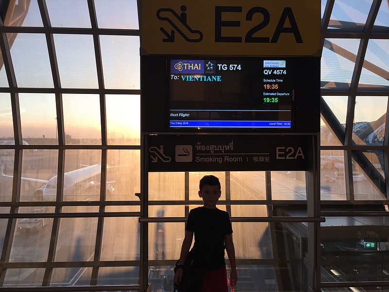 This May 5, 2016 photo shows Wyatt Anthony silhouetted under a sign while awaiting a flight at Bangkok's Suvarnabhumi Airport. Wyatt occasionally travels with just one of his parents while his sibling and other parent remain at home _ a type of trip that offers valuable opportunities for bonding, says Dr. Gary Bingham, an associate professor at Georgia State University, who studies the impact of high-quality adult-child interactions. (AP Photo/Ted Anthony)