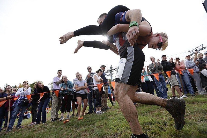 
              FILE - In this Oct. 8, 2016 file photo, Jaime Devine is carried by her husband, Thomas Devine, of Boston, Mass., during the North American Wife Carrying Championship at the Sunday River Ski Resort in Newry, Maine.  Dozens of participants are vying for cash and beer  in the North American Wife Carrying Championship. More than 60 couples are registered, and more are on a waiting list, for the annual event Saturday, Oct. 7, 2017 at the Sunday River in Maine.(AP Photo/Robert F. Bukaty, File)
            