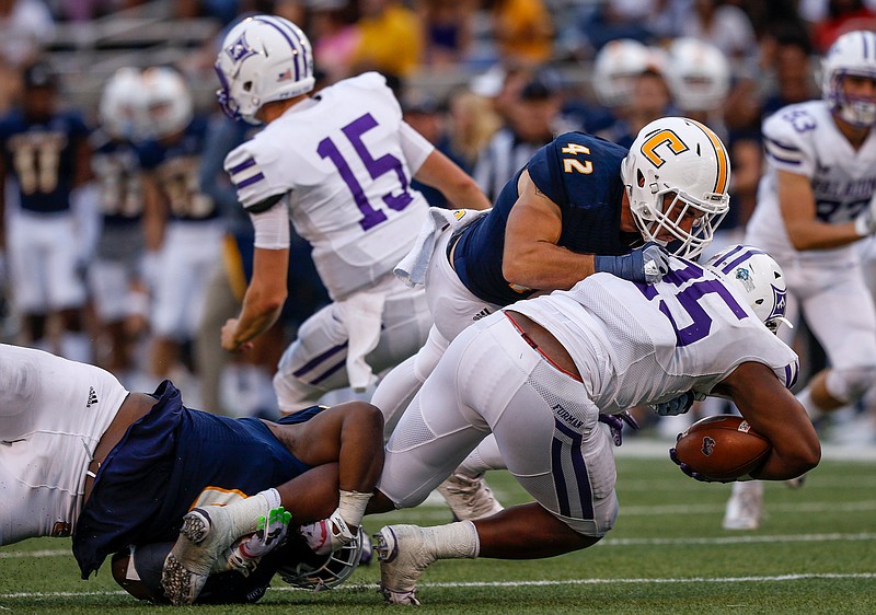 UTC defensive lineman Isaiah Mack, left, and UTC defensive lineman Hawk Schrider (42) tackle Furman running back Antonio Wilcox during the Mocs' home football game against the Furman Paladins at Finley Stadium on Saturday, Oct. 7, 2017, in Chattanooga, Tenn.