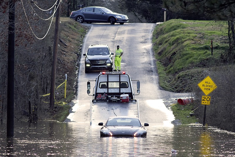 A wrecker prepares to pull a stranded car out of the floodwaters of Mackey Branch that covered Davidson Road in February 2016.