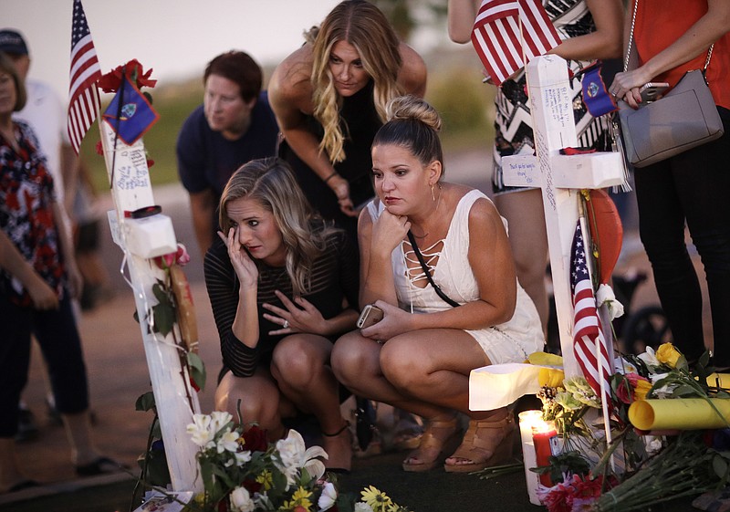 From left, Rachel Shepherd, Jamie Lambert and Annie Leach visit a makeshift memorial for victims of a mass shooting Friday, Oct. 6, 2017, in Las Vegas. Stephen Paddock opened fire on an outdoor country music concert on Sunday killing dozens and injuring hundreds. (AP Photo/John Locher)