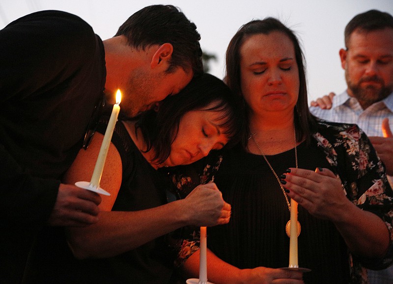 
              From left, Ryan Donato, Heather Barclay and her sister Tracy Gyurina grieve at a candlelight vigil for Nicol Kimura, a victim of the Las Vegas mass shooting, at Sierra Vista Elementary School in Placentia, Calif., Sunday, Oct. 8, 2017. (AP Photo/Reed Saxon)
            