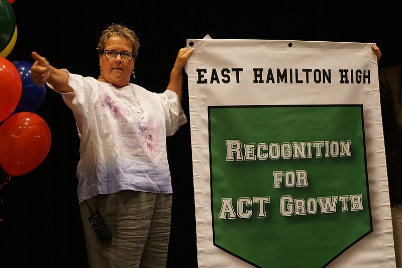 Principal Gail Chuy gives a thumbs up to East Hamilton High School students as she shows off a banner to celebrate the school's improved ACT scores in 2016.