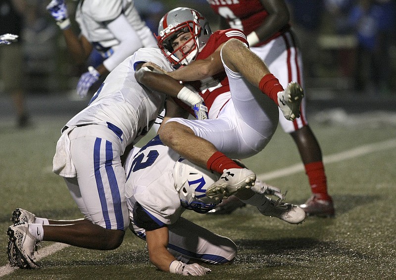 McCallie's Shannon Walker, left, and Zack McAteer (42) hit Baylor's Mats Pokela after Pokela's punt was blocked for an early score at Baylor's Heywood Stadium on Friday. The visiting Blue Tornado won 40-14.