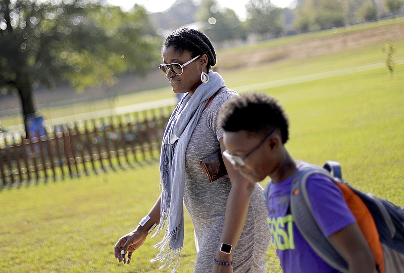 
              Corrie Davis, left, picks up her son Turner from Big Shanty Elementary School in Kennesaw, Ga., Wednesday, Oct. 11, 2017. A new battle line has formed in the national debate over Civil War flags and symbols. The school last month invited fifth-graders to dress up as characters from the Civil War. Davis says a white student dressed as a plantation owner approached her son and said "You are my slave." Davis says she wants Cobb County school officials to understand the pain that caused her son. She also wants the school to stop the annual Civil War dress-up day. (AP Photo/David Goldman)
            