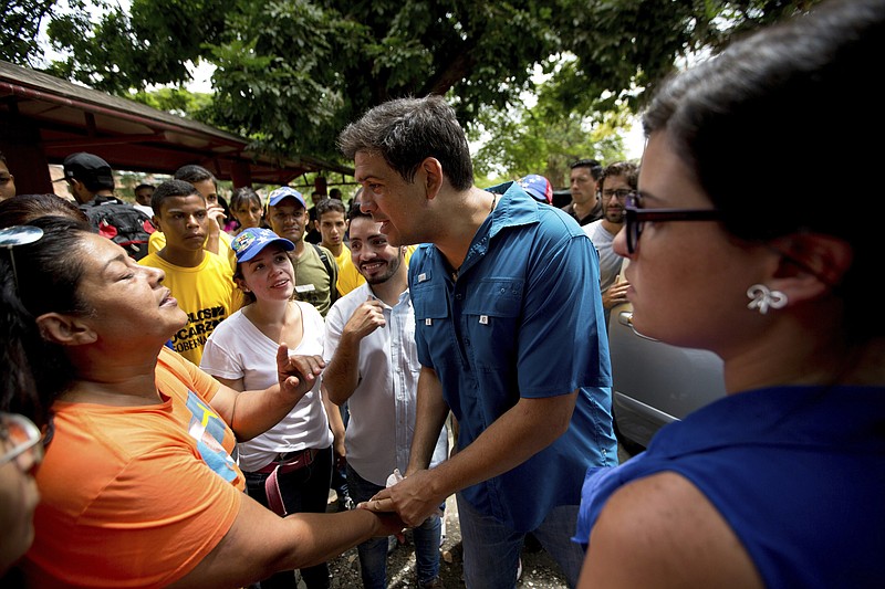 
              In this Oct. 7, 2017 photo, opposition candidate Carlos Ocariz, who is running for governor of Miranda state, speaks with a woman as he campaigns in Guarenas, on the outskirts of Caracas, Venezuela. Polls project opposition candidates like Ocariz are likely to win a majority of the 23 governorships up for grabs Sunday, Oct. 15 in a vote that could usher in a major political shift for the country. (AP Photo/Fernando Llano)
            