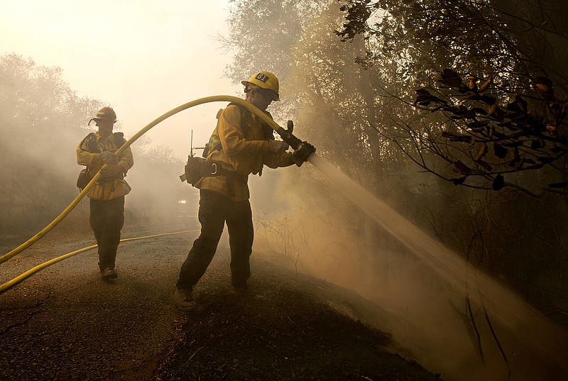 
              Santa Paula firefighter Tyler Zeller, right, hoses down a hot spot with the help of Jesse Phillips, Thursday, Oct. 12, 2017, in Sonoma, Calif. Firefighters from across the state have been brought in to help battle the blazers that started Sunday night. (AP Photo/Rich Pedroncelli)
            