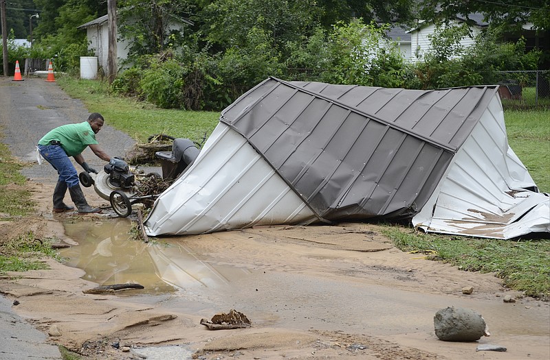 In this Jul 11, 2013, staff file photo, Tony Chubb pulls a lawnmower out of his destroyed storage building Thursday as South Pittsburg residents deal with the aftermath of flash flooding. Floodwaters moved the building more than 50 feet from the spot where it was anchored behind his house.