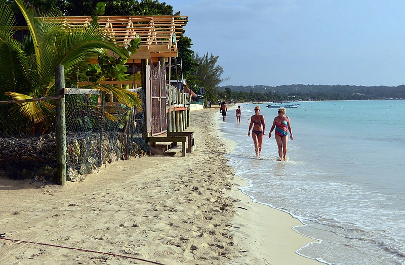 Sunbathers walk along a patch of resort-lined crescent beach in Negril in western Jamaica. While some islands in the Caribbean were hard-hit by this season's hurricanes, others were relatively unscathed and are open for business as usual.