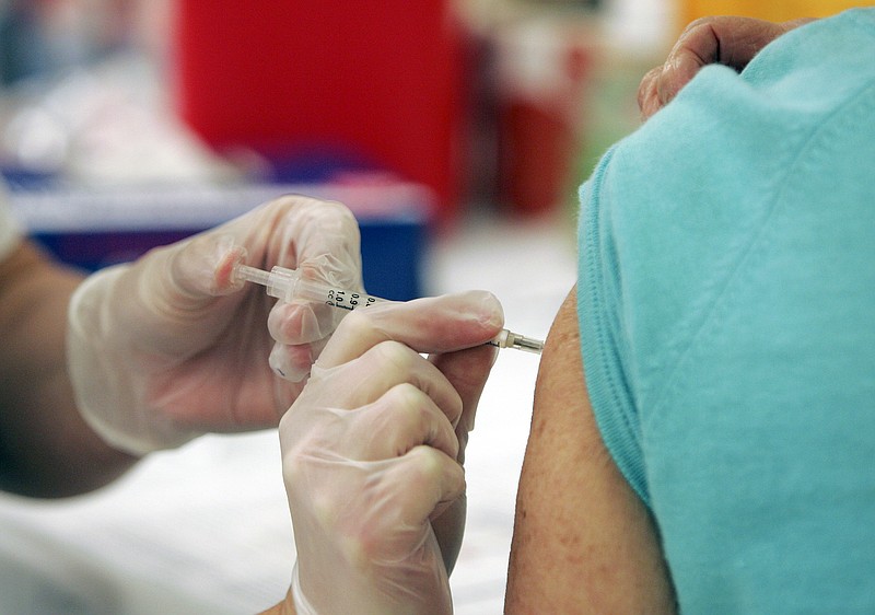 A Walgreens pharmacy manager injects a costumer with the seasonal flu vaccine. Experts advise getting a flu shot in October before flu season actively begins.