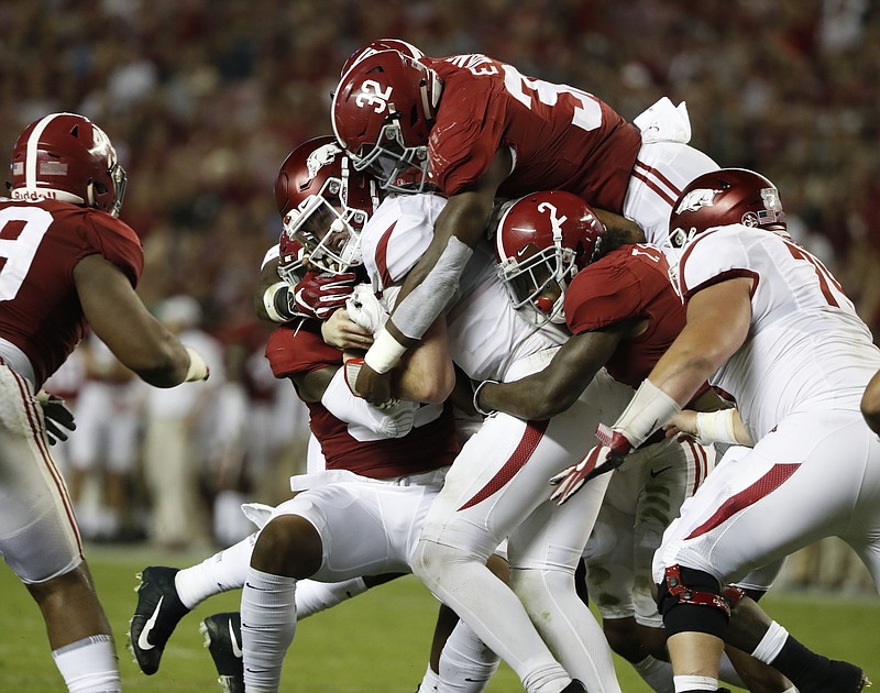 Linebacker Rashaan Evans top, defensive back Tony Brown , right, and other Alabama defenders team up to bring down 6-foot-7, 268-pound Arkansas quarterback Cole Kelley during Saturday night's 41-9 win by the Crimson Tide.