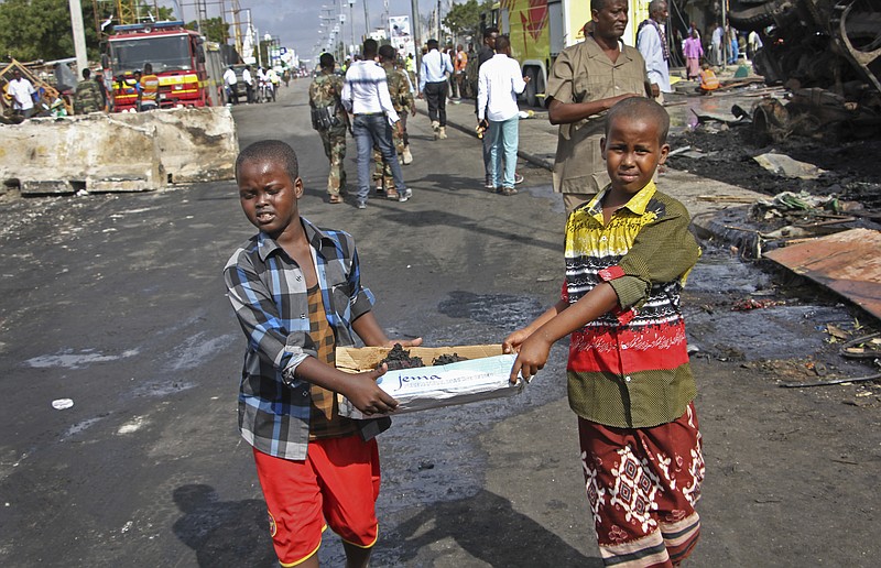 
              Somali children assist other civilians and security forces in their rescue efforts by carrying away unidentified charred human remains in a cardboard box, to clear the scene of Saturday's blast, in Mogadishu, Somalia, Sunday, Oct. 15, 2017. The death toll from the huge truck bomb blast in Somalia's capital rose to over 50 Sunday, with more than 60 others injured, as hospitals struggled to cope with the high number of casualties, security and medical sources said. (AP Photo/Farah Abdi Warsameh)
            