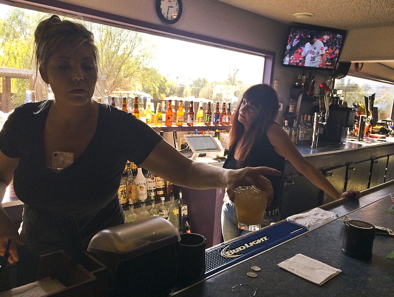 
              Crystal Maples, left, and Sally Kyle pour drinks at McCarty's Bar which turned into an evacuation center in Redwood Valley, Calif., Saturday, Oct. 14, 2017. Bartender Maples fled the wildfire after a harrowing escape to the bar Monday, and opened it to evacuees, many of which spent several days here. Mendocino County is 70 miles north of California’s fabled wine country now under siege from wildfires but a world away in mood, attitude and, especially, prominence. (AP Photo/Paul Elias)
            