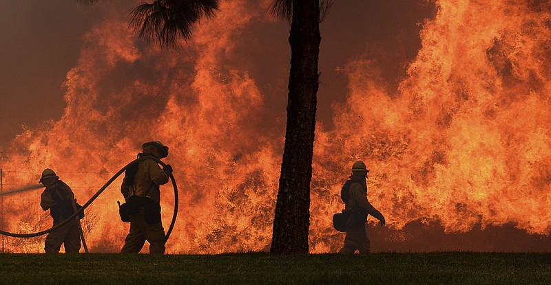 
              FILE--In this Oct. 9, 2017, file photo, firefighters battle flames along Jamboree Road in Orange, Calif. The long and brutal 2017 wildfire season is stressing the state and federal agencies that have to pay for the army of ground crews and machinery required to fight them. (Will Lester/The Orange County Register via AP, file)
            