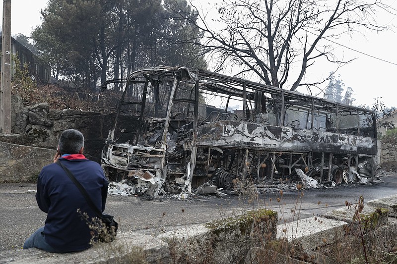 
              A man looks at the remains of a burned coach after a wild fire in Pontevedra, in the northwestern Spanish region of Galicia, Spain on Monday, Oct. 16, 2017. Authorities in Portugal and Spain say that nine people died over the weekend in hundreds of wildfires fanned by strong winds caused by a hurricane.(AP Photo/Lalo R. Villar)
            