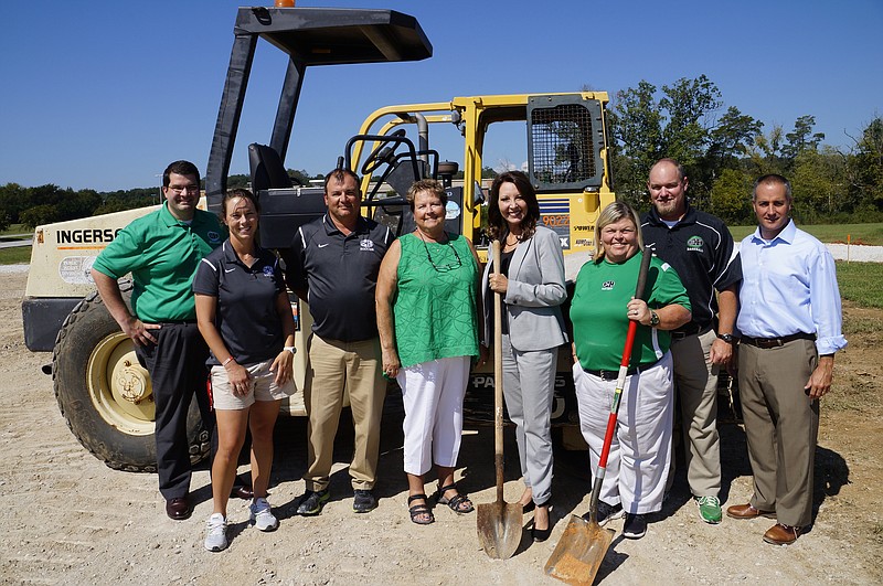 Matt Thurman, Carrie Hill, Patrick Daverson, Gail Chuy, Sabrena Smedley, Norma Nelson, Steve Garland and Joe Wingate, from left, stand by a road-roller near East Hamilton Middle/High School's soccer and baseball fields. The site will soon have a new 174-car parking lot. (Staff photo by Myron Madden)