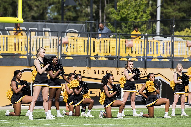 
              In this Saturday, Sept. 30, 2017 photo, five Kennesaw State University cheerleaders take a knee during the national anthem prior to a college football game against North Greenville, in Kennesaw, Ga. The group of cheerleaders from the college in Georgia say they'll take a knee in the stadium tunnel when the national anthem is played at Saturday's homecoming game since their university moved them off the field after an earlier demonstration. (Cory Hancock/Atlanta Journal-Constitution via AP)
            