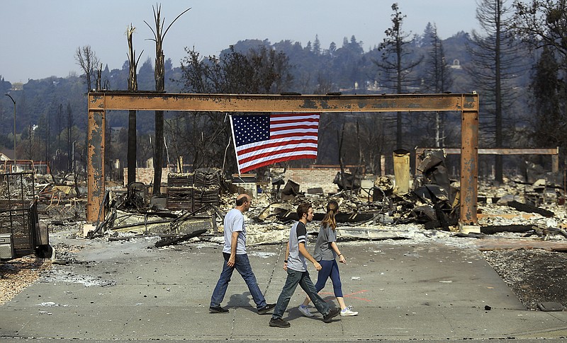 
              From left, Rick Olcese, Ty Knapp and Ariana Olcese search for the Olcese family cats in the Larkfield neighborhood, Monday Oct. 16, 2017, near Santa Rosa, Calif. Calm winds gave an advantage to firefighters trying to tame the flames of deadly wildfires on Monday. (Kent Porter/The Press Democrat via AP)
            