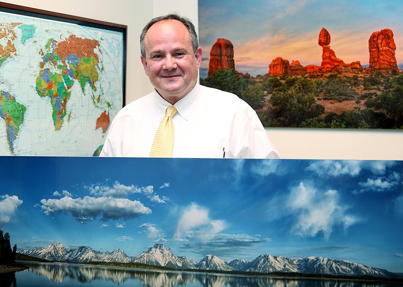 Michael Tomshack poses for a photo with some of his photographs that decorate his office at Morgan Stanley on Monday, Oct. 16, 2017, in Chattanooga, Tenn. Tomshack volunteers for several charities around Chattanooga providing his photo services.