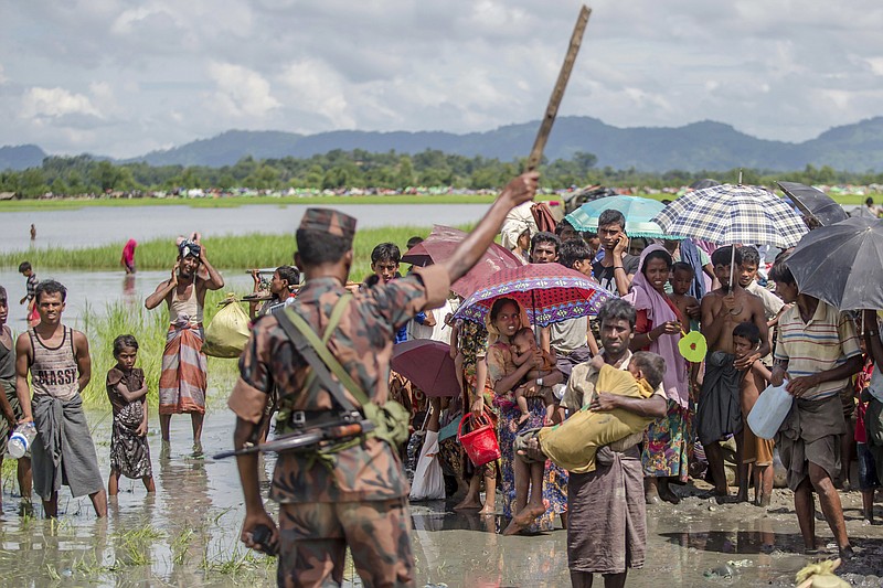 A Bangladesh border guard soldier stops newly arrived Rohingya Muslims, who crossed over from Myanmar into Bangladesh, from moving ahead towards refugee camps, at Palong Khali, Bangladesh, Tuesday, Oct. 17, 2017. Thousands more Rohingya Muslims are fleeing large-scale violence and persecution in Myanmar and crossing into Bangladesh, where more than half a million others are already living in squalid and overcrowded camps, according to witnesses and a drone video shot by the U.N. office for refugees. (AP Photo/Dar Yasin)