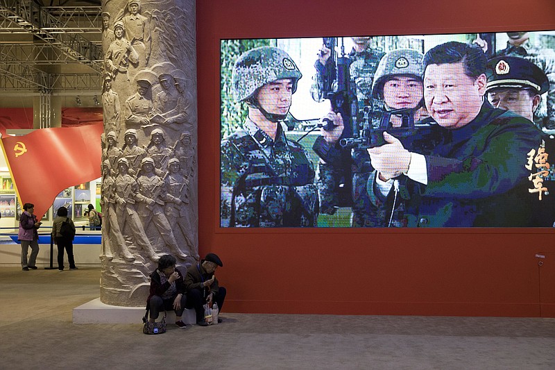 In this Thursday, Oct. 19, 2017, photo, video showing Chinese President Xi Jinping handling an assault rifle is shown at an exhibition highlighting China's achievements under five years of his leadership at the Beijing Exhibition Hall in Beijing. Xi is channeling a red-blooded nationalism as he seeks to strengthen the Communist Party's role in Chinese life and assert Beijing's rise as a global superpower. Xi's muscular foreign policy could become even more assertive following this month's party congress, where he's expected to get a second five-year term as party secretary general. (AP Photo/Ng Han Guan)