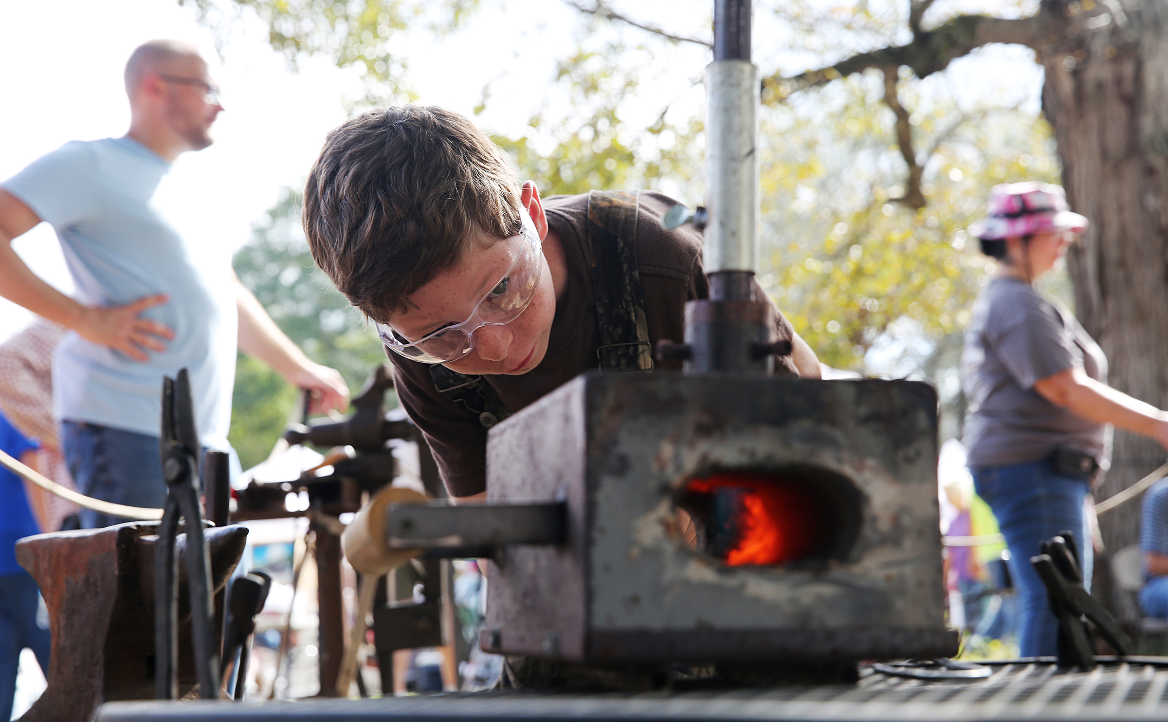 Joshua Newton, 11, looks into a gas forge as he heats up a piece of metal to hammer out into a hook during the 40th annual Ketner's Mill Country Arts Fair in Whitwell, Tenn., Sunday, Oct. 22, 2017. Newton is a third generation blacksmith, and he made his first complete knife for the festival.