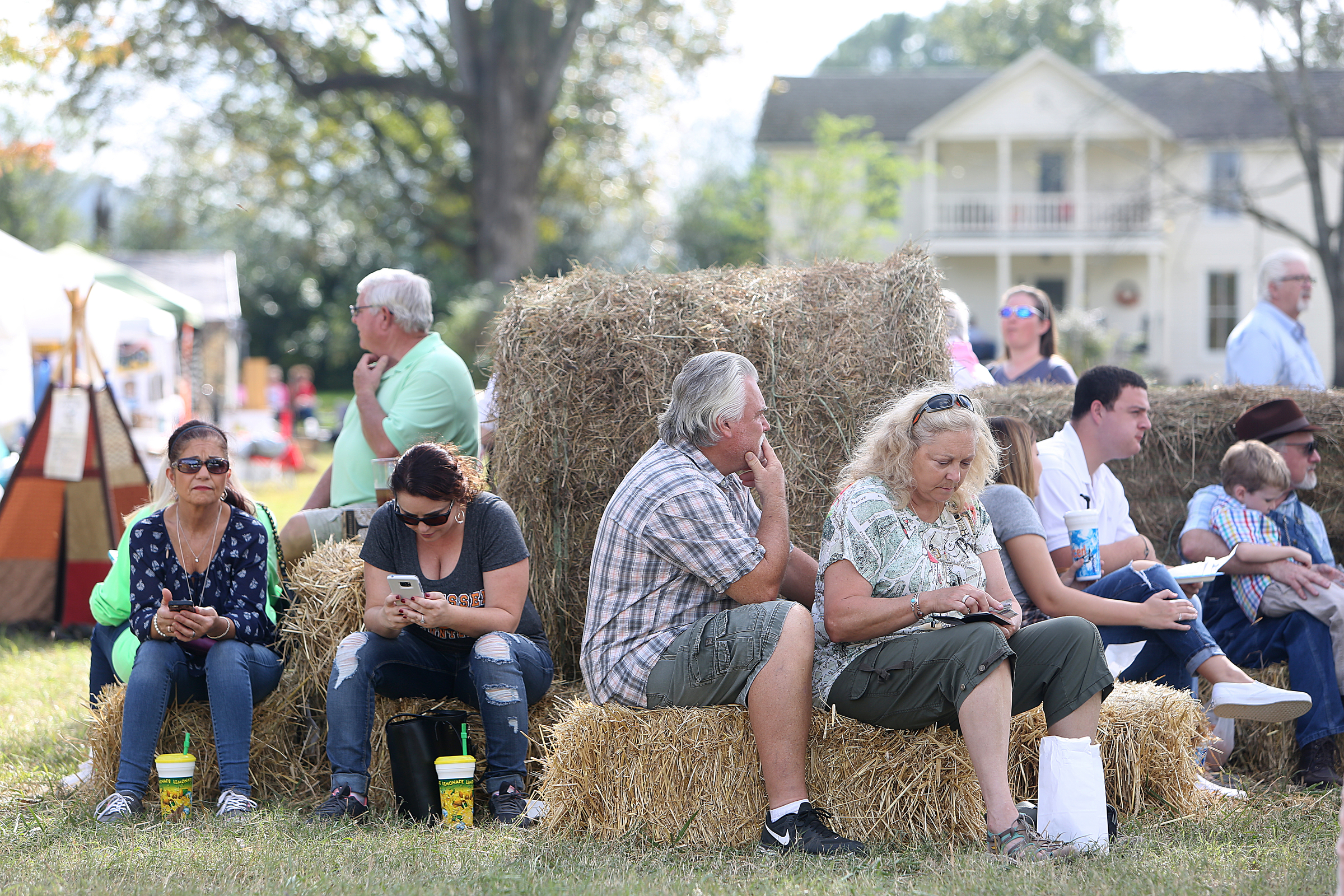 Fair-goers take a break from shopping on a stack of hay bales during the 40th annual Ketner's Mill Country Arts Fair in Whitwell, Tenn., Sunday, Oct. 22, 2017. Each year more than 150 artisans show off their work through products and demonstrations at the festival.