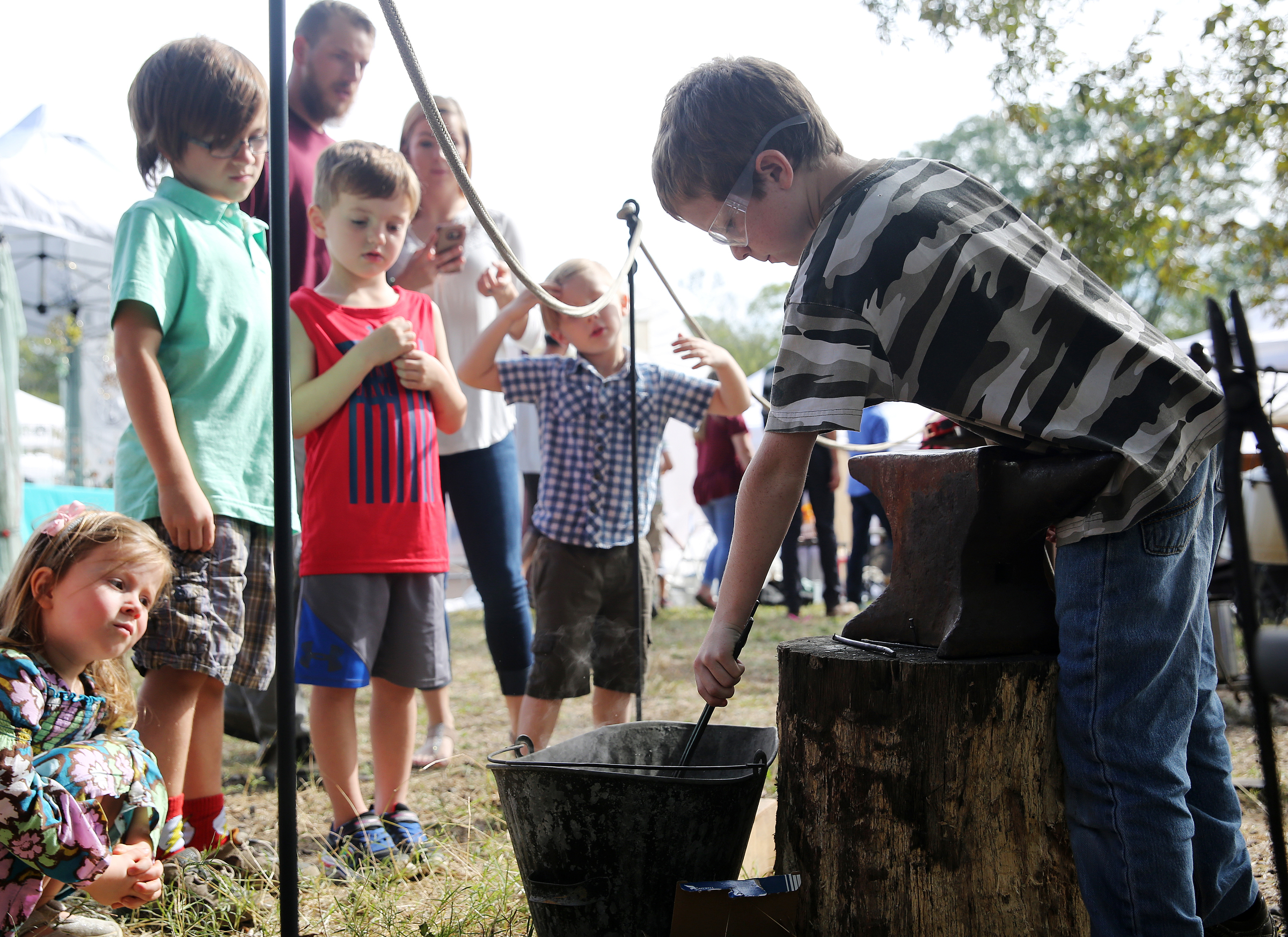 Samuel Newton, 8, cools off a horseshoe nail that he was bending into a hook as others look on during the 40th annual Ketner's Mill Country Arts Fair in Whitwell, Tenn., Sunday, Oct. 22, 2017. The fair was established in 1977 to help preserve the mill.