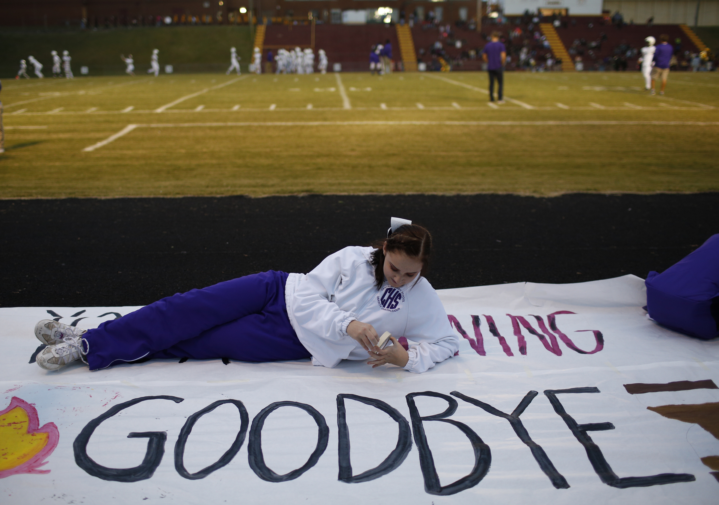 Central cheerleader Meghan Duncan tapes up the banner before their prep football game at Tyner High School on Friday, Oct. 27, 2017, in Chattanooga, Tenn.