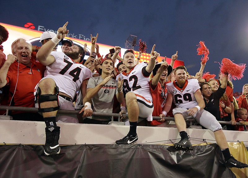 Georgia players from left, Ben Cleveland (74), Cameron Nizialek (92) and Trent Frix (69) celebrate with fans after defeating Florida 42-7 in an NCAA college football game, Saturday, Oct. 28, 2017, in Jacksonville, Fla. Georgia won 42-7. (AP Photo/John Raoux)