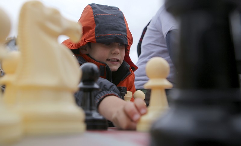 Six-year-old Jackson Smalley plays chess against his dad during the Glass Street Live! stop of the City Celebration and Ciclovia on Sunday, Oct. 29, 2017 in Chattanooga, Tenn. The Celebration and Civlovia was a 4-mile rolling block party with stops in five East Chattanooga neighborhoods.