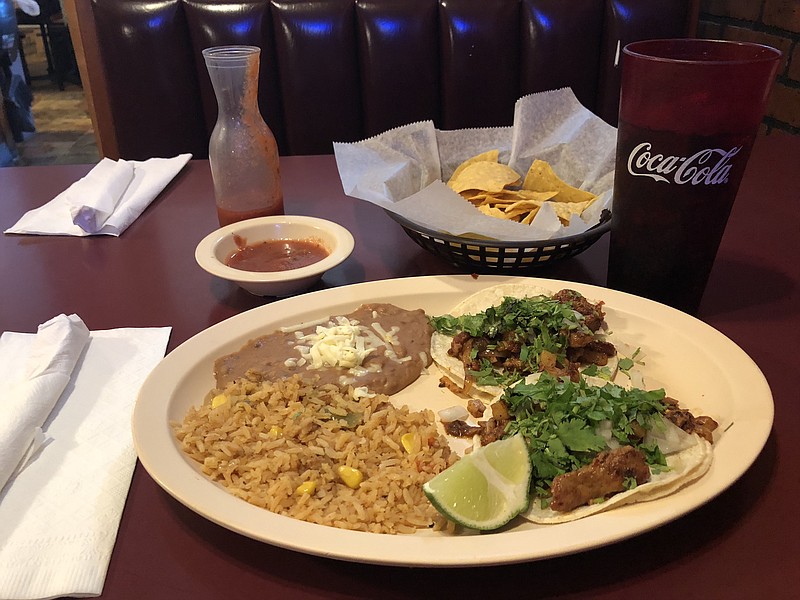 Two Mexico City-style tacos filled with pork are served with refried beans and a side of Mexican rice in a $5.99 special at La Altena.