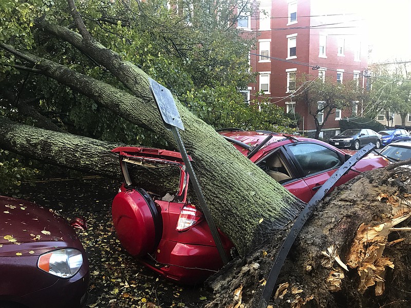 A large tree is down on top of a car on Mellen Street, in Portland, Maine, Monday, Oct. 30, 2017, after early morning storm with high winds. Central Maine Power, the state's largest utility, said its 391,000 outages surpasses its peak of 345,000 homes and businesses without power during the ice storm of 1998. (Michele McDonald/Portland Press Herald via AP)