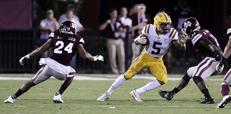 LSU running back Derrius Guice (5) tries to escape Mississippi State defensive back Chris Rayford (24) and linebacker Dezmond Harris (11) during their SEC matchup in September.