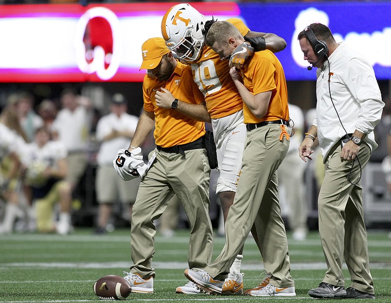Tennessee football coach Butch Jones, center, checks on injured tight end Eli Wolf during a home game against Indiana State in September. BELOW: Darrell Taylor played with his injured right hand in a cast during the game against Indiana State.