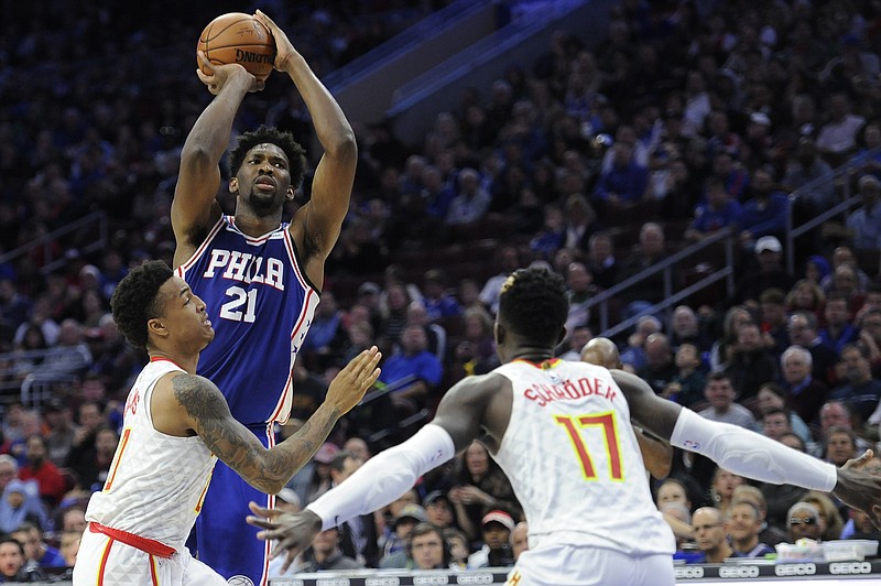 Philadelphia 76ers' Joel Embiid (21) takes a shot over Atlanta Hawks' John Collins (20) and Atlanta Hawks' Dennis Schroder (17) during the first half of an NBA basketball game, Wednesday, Nov. 1, 2017, in Philadelphia. (AP Photo/Michael Perez)