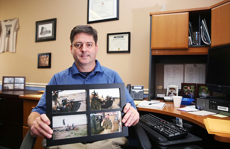 Chuck Ayars, an Iraq war veteran, poses for a portrait in his office at the Chattanooga Vet Center holding photos of himself Tuesday, Oct. 31, 2017, in Chattanooga, Tenn. In November 2004, Ayars was injured when a member of al-Qaeda detonated a bomb in a car while he and others in his platoon drove by in a Humvee.