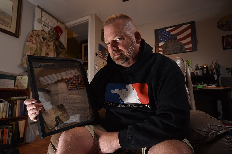 Billy Massingale, 49, of Cleveland, holds a creative art compilation shadow box made by his middle daughter, Sabra, inside his man cave. Massingale began service in the 82nd Airborne. Then, served with various long range divisions of Company H121st and Echo Company 51st in Iraq. Finally, he became a special advisor to the Afghan army. "I just love it," Massingale said.