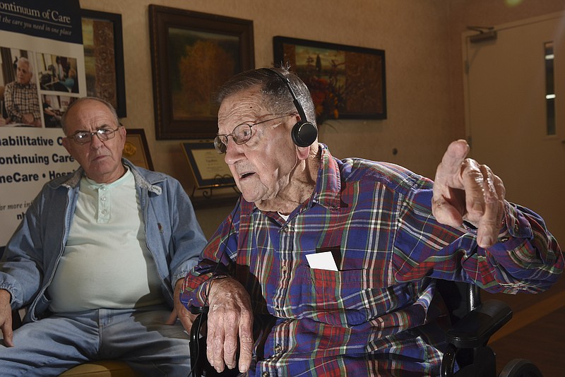 In the lobby of NHC Health Care in Rossville, Floyd Brown, 99, talks about his time in the U.S. Army in Germany during WWII. Brown's nephew, Don Brown, left, listens.