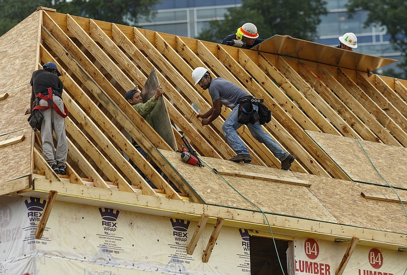 Workers install a roof on a town home in the Cameron Harbor development on Riverfront Parkway on Thursday, July 6, 2017, in Chattanooga, Tenn.