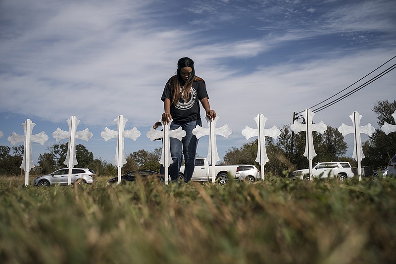 Sheree Rumph of San Antonio, prays over crosses that were put up outside a gas station in Sutherland Springs, Texas, Monday. A gunman killed at least 26 people and injured at least 20 more during a late-morning church service in Sutherland Springs a day earlier. (Todd Heisler/The New York Times)