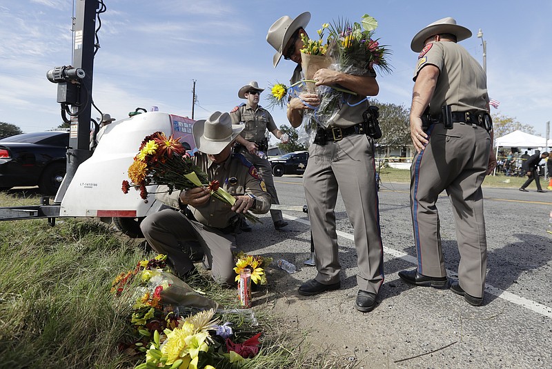Law enforcement officials move flowers left at the scene of a shooting at the First Baptist Church of Sutherland Springs, Monday, Nov. 6, 2017, in Sutherland Springs, Texas. A man opened fire inside the church in the small South Texas community on Sunday, killing and wounding many. (AP Photo/Eric Gay)