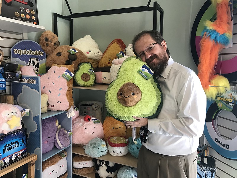 Mountain Top Toys owner and Mountain Business Association President Patrick Holland hugs an avocado plush toy from Squishable, one of the store's top-sellers. (Staff photo by Emily Crisman)