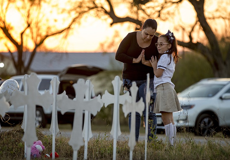 Meredith Cooper, of San Antonio, Texas, and her 8-year-old daughter, Heather, visit a memorial of 26 metal crosses near First Baptist Church in Sutherland Springs, Texas, Monday Nov. 6, 2017. The gunman of a deadly shooting at the small-town Texas church had a history of domestic violence and sent threatening text messages to his mother-in-law, a member of First Baptist, before the attack, authorities said Monday. (Jay Janner/Austin American-Statesman via AP)