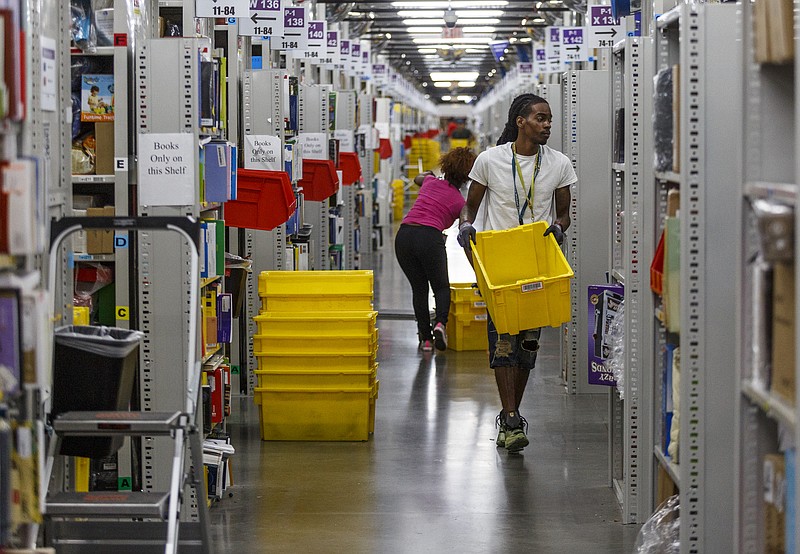 Staff file photo by Doug Strickland / Workers fill yellow totes with merchandise in the pick mod area of the Amazon Fulfillment Center in Enterprise South Industrial Park this summer.