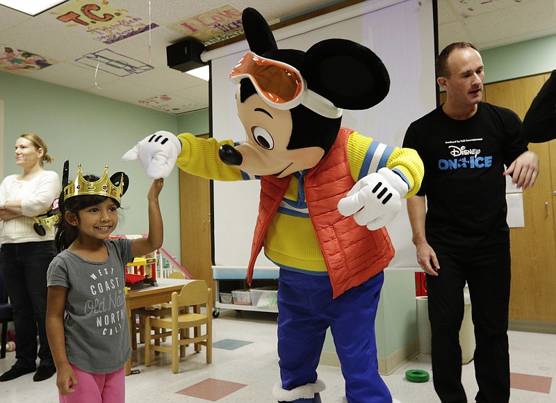 Mickey Mouse twirls Leslie Martinez, left, as figure skater Mathew King stands nearby during a visit by Disney on Ice to Erlanger Children's Hospital on Wednesday, Nov. 8, 2017, in Chattanooga, Tenn. Mickey and two figure skaters met with children to help make their stays in the hospital a little easier.