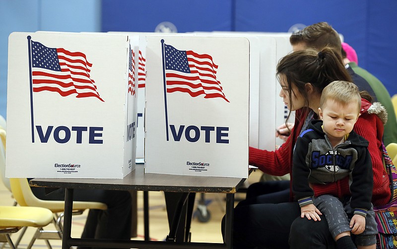 Karina Smith holds her son Kyler Smith, 2, as she fills out her ballot at a polling place Tuesday, Nov. 7, 2017, in Alexandria, Va. Republican candidate for Virginia governor Ed Gillespie faces Democrat Lt. Gov. Ralph Northam in Tuesday's election. (AP Photo/Alex Brandon)